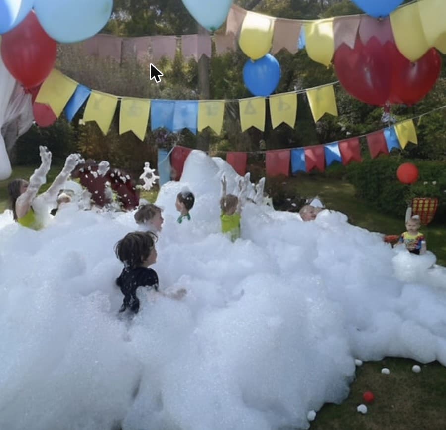 Kids playing in foam under a balloon archway at a Daydream Bubble Parties event